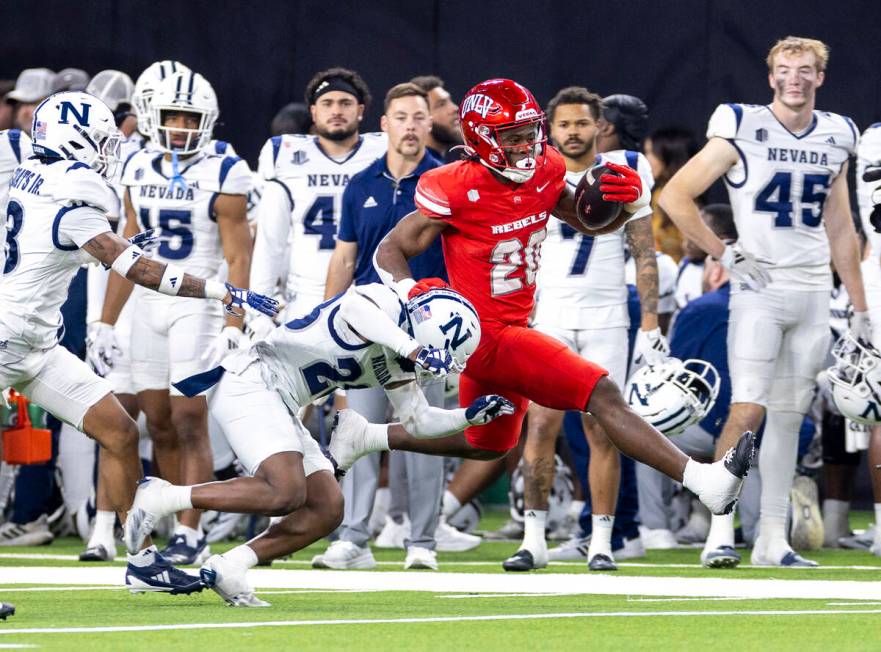 UNLV running back Kylin James (20) avoids UNR tacklers during the NCAA college football game at ...