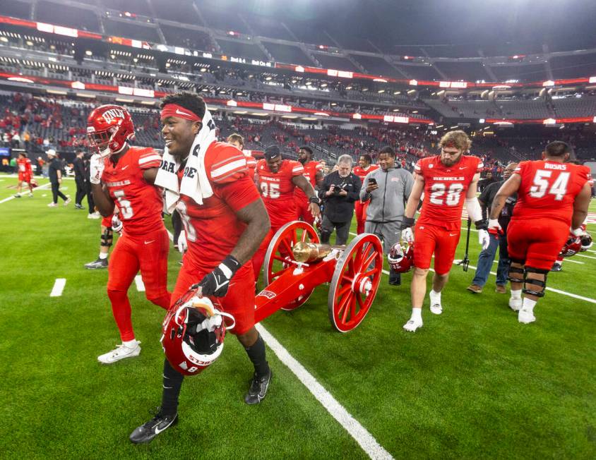 UNLV running back Greg Burrell (5) and linebacker Marsel McDuffie (8) wheel the Fremont Cannon ...