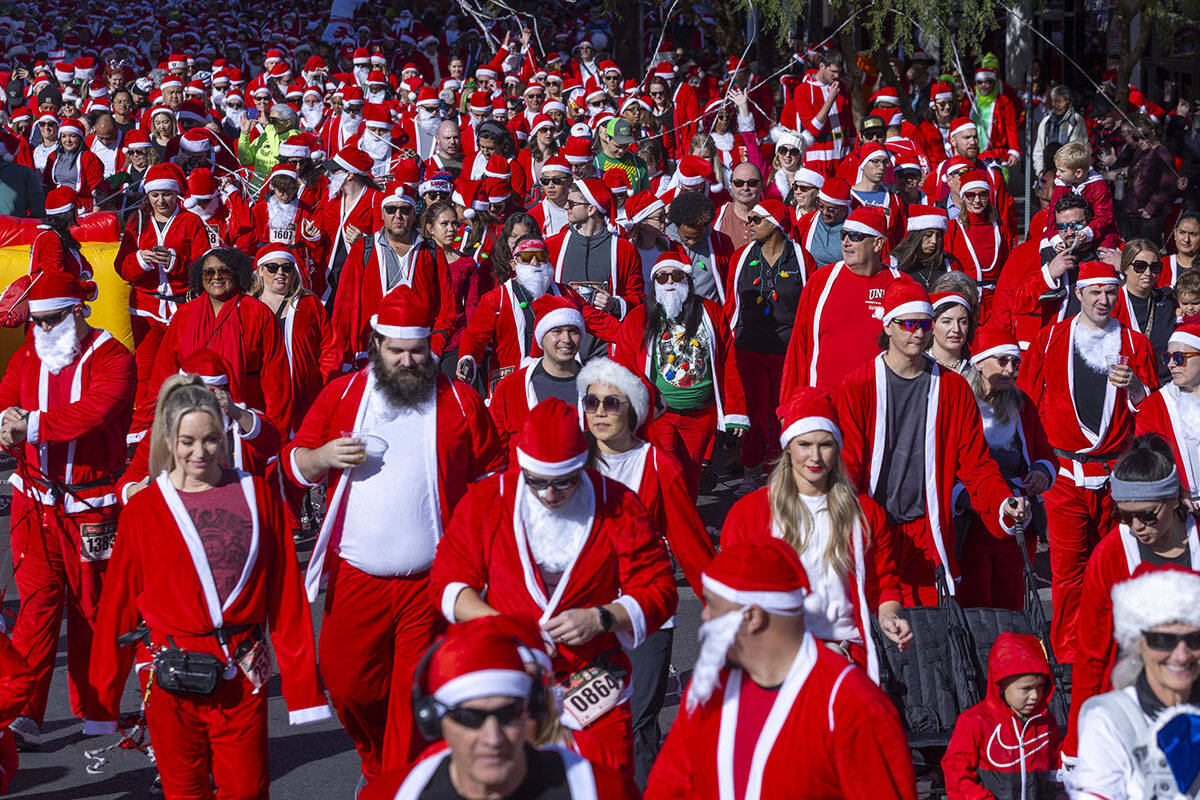 Participants in the 5K run leave the starting line during the Las Vegas Great Santa Run through ...