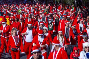 Participants in the 5K run leave the starting line during the Las Vegas Great Santa Run through ...