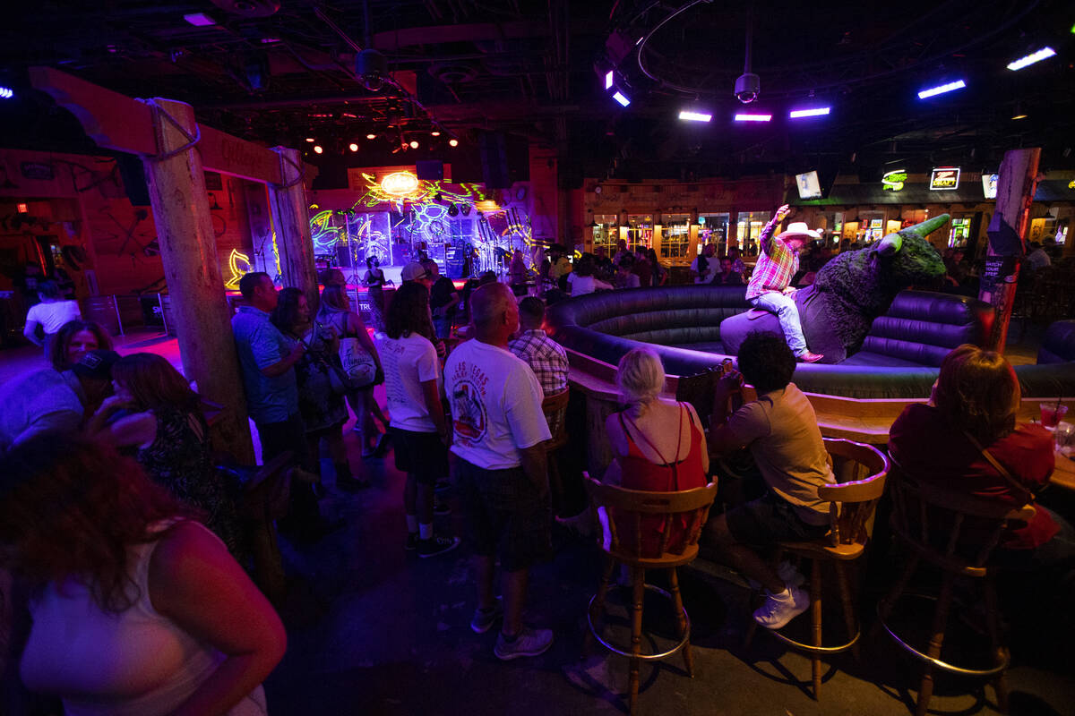 People watch a person ride a mechanical bull at Gilley's Saloon inside of Treasure Island hotel ...