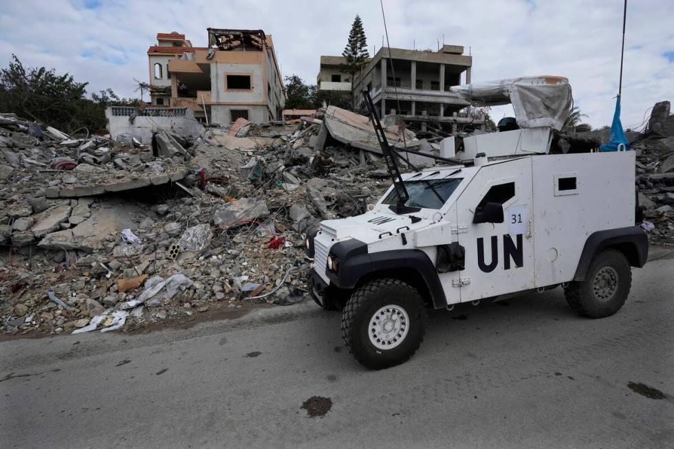 A South Korean U.N peacekeeper armoured vehicle drives by destroyed buildings in Chehabiyeh vil ...