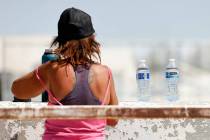 A homeless person fills out her water bottle, delivered by a Help of Southern Nevada outreach w ...