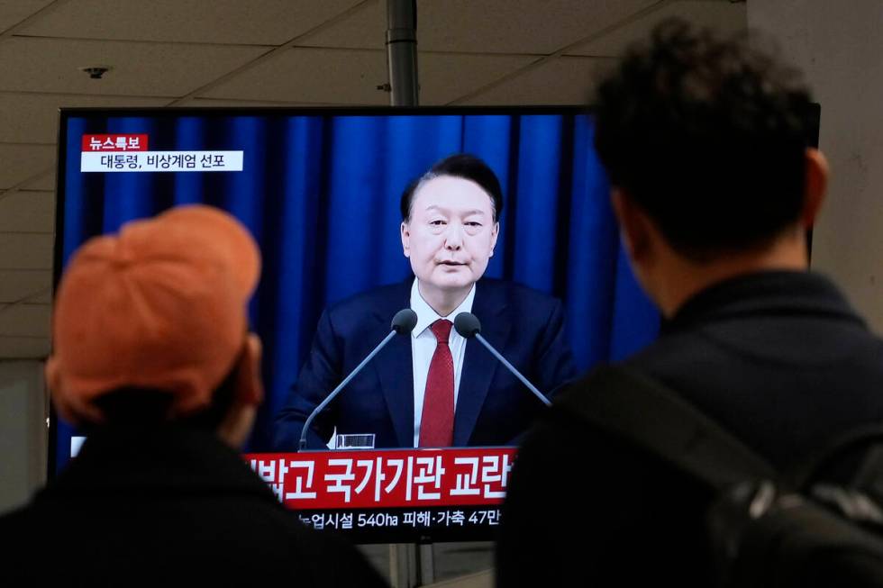 People watch a TV screen showing South Korean President Yoon Suk Yeol's televised briefing at a ...