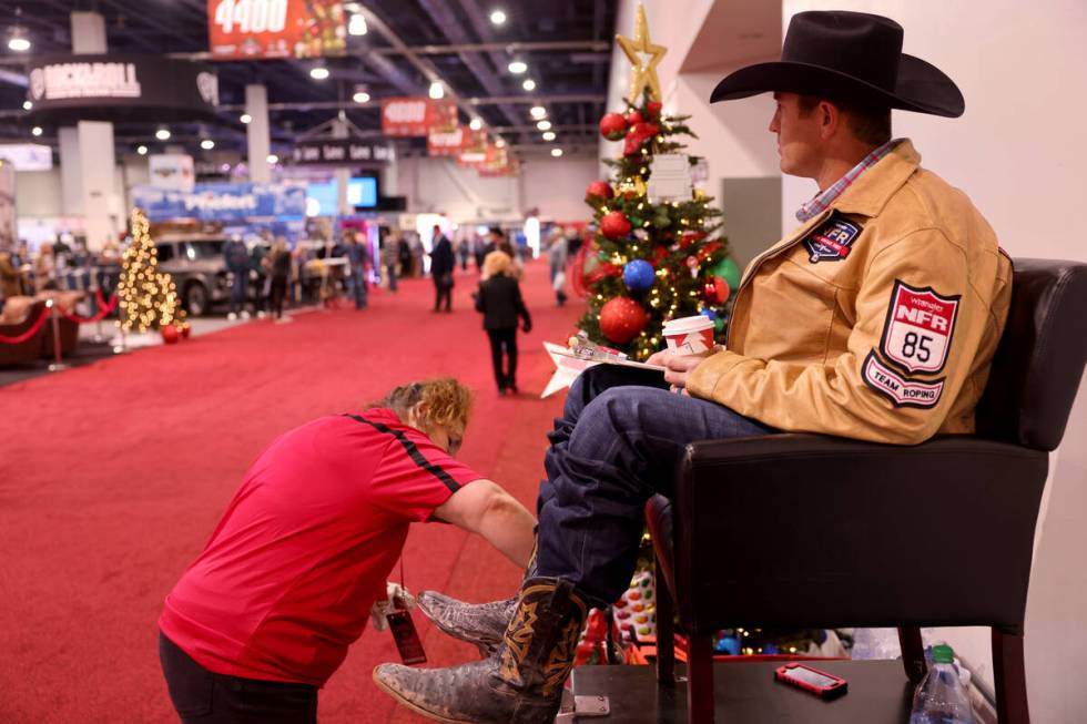 Team roper Rhen Richard gets his boots shined by Mia Asturi during Cowboy Christmas at the Las ...