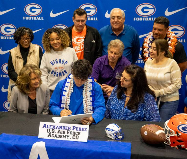 Bishop Gorman defensive back Alexander Perez, center, signs a financial aid agreement with the ...