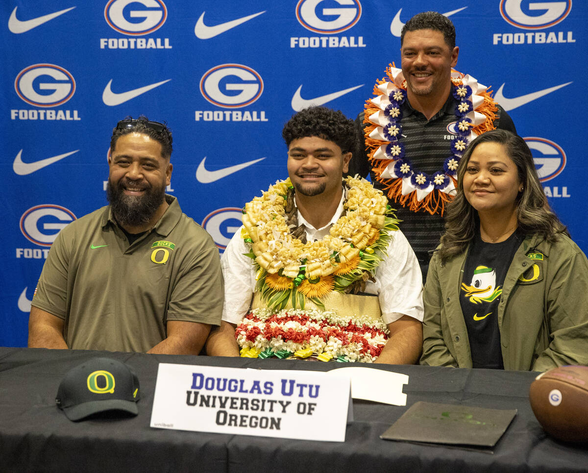 Bishop Gorman offensive lineman Douglas Utu, center, signs a financial aid agreement with the U ...