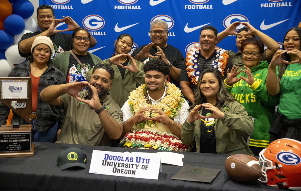 Bishop Gorman offensive lineman Douglas Utu, center, signs a financial aid agreement with the U ...