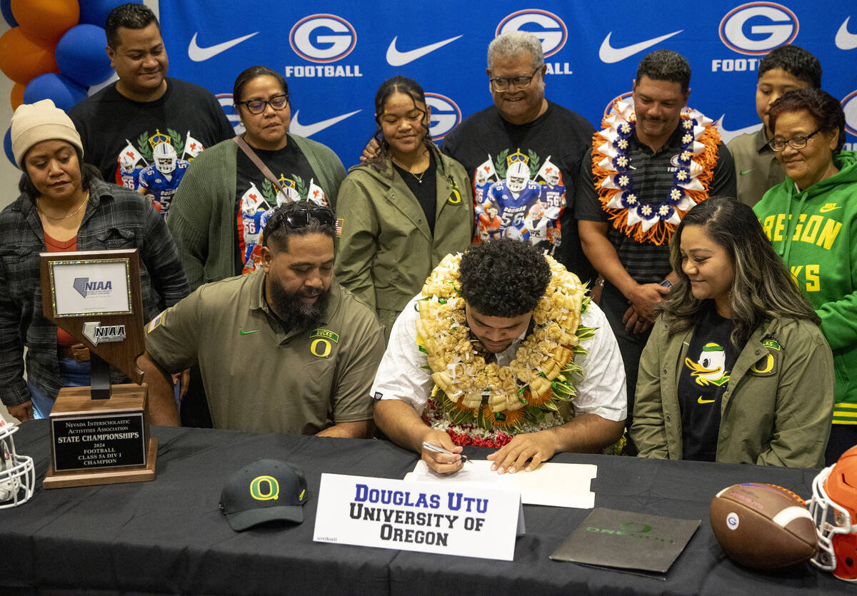 Bishop Gorman offensive lineman Douglas Utu, center, signs a financial aid agreement with the U ...