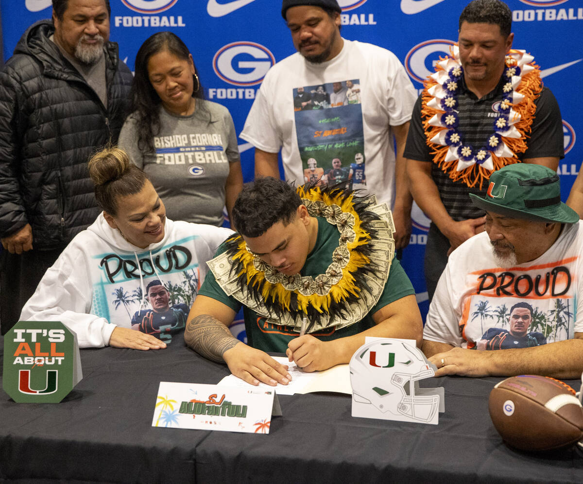 Bishop Gorman offensive lineman SJ Alofaituli, center, signs a financial aid agreement with the ...