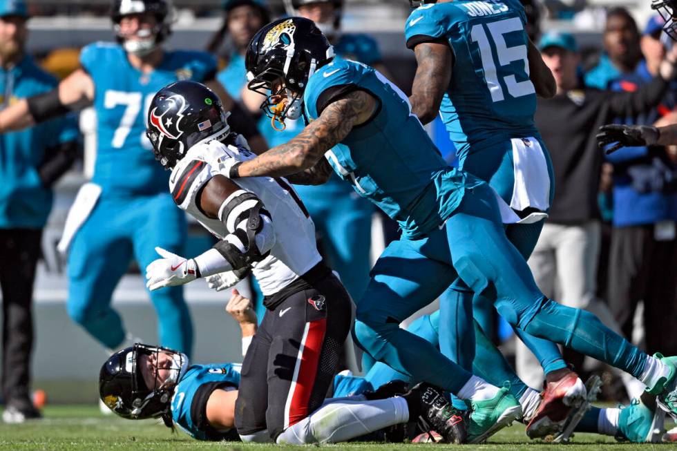 Jacksonville Jaguars tight end Evan Engram (17, right) jumps on Houston Texans linebacker Azeez ...