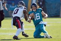 Jacksonville Jaguars quarterback Trevor Lawrence (16) slides in front of Houston Texans linebac ...