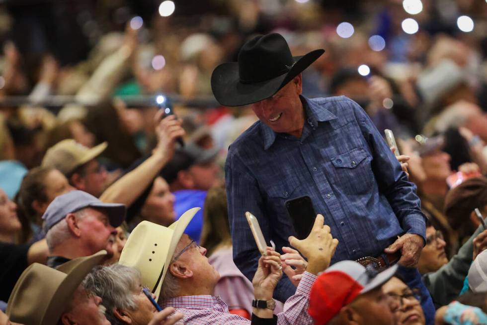 A rodeo fan smiles as others wave their phone lights during the final day of the National Final ...