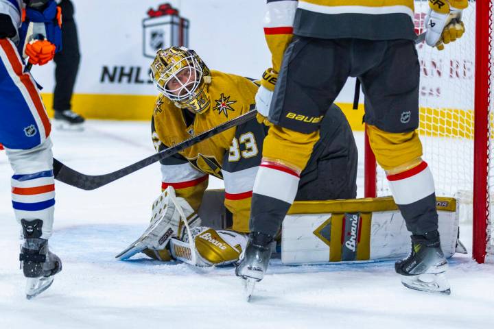 Golden Knights goaltender Adin Hill (33) looks up to teammate defenseman Shea Theodore (27) aft ...