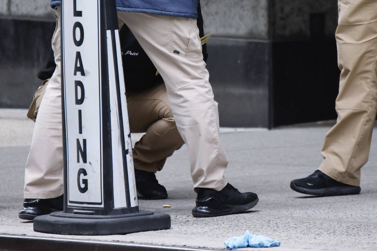 Members of the New York police crime scene unit investigate bullets lying on the sidewalk at th ...