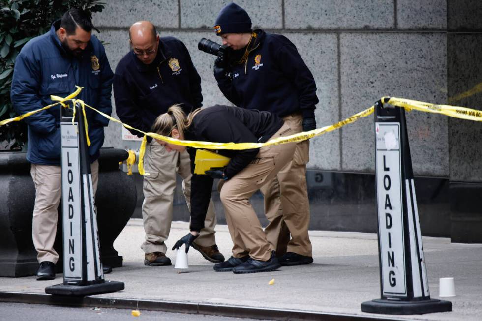 Members of the New York police crime scene unit pick up cups marking the spots where bullets li ...