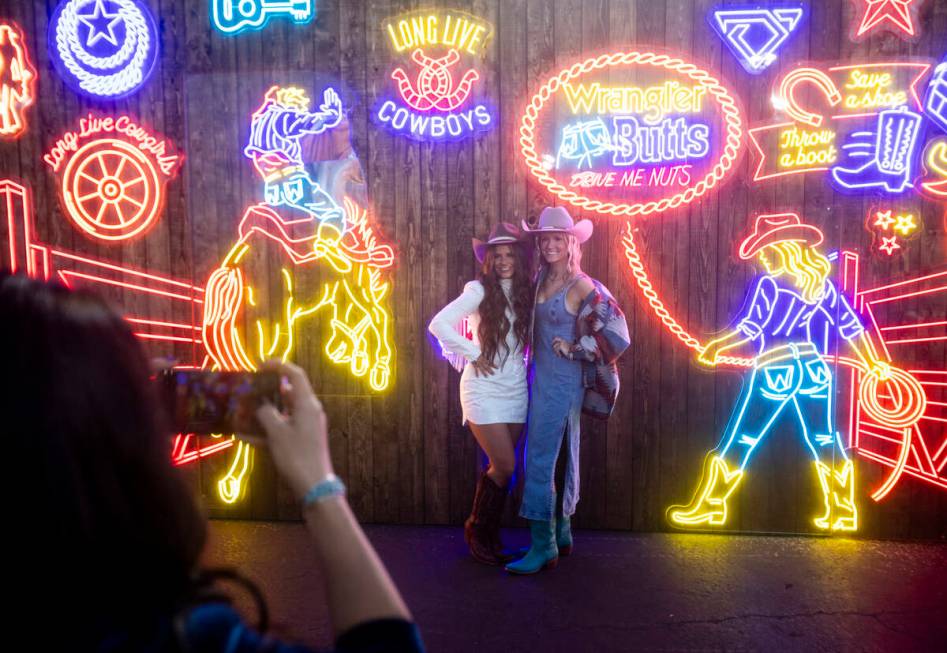 Brooklyn Irwin, left, and Ava Maslen, right, of Oregon, pose in front of neon signs before open ...