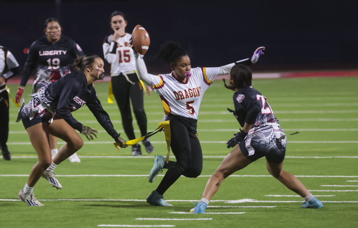 Del Sol’s Joselynn Carrington (5) runs the ball between Liberty defenders during a flag ...