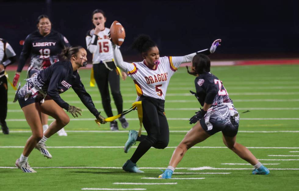 Del Sol’s Joselynn Carrington (5) runs the ball between Liberty defenders during a flag ...