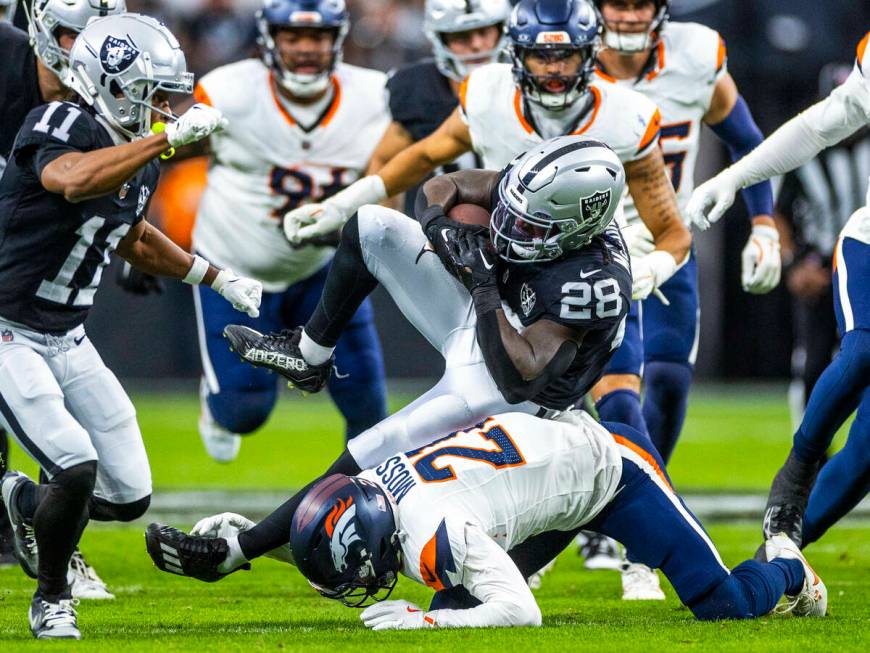 Raiders running back Sincere McCormick (28) is stopped on a run by Denver Broncos cornerback Ri ...