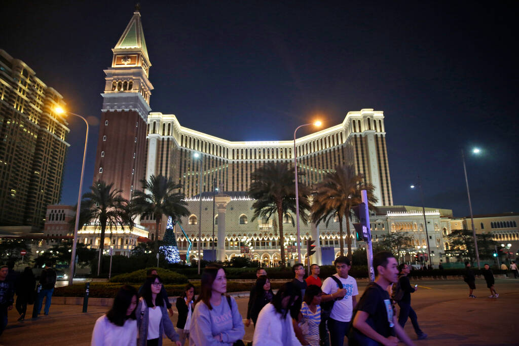 People walk in front of the Venetian Macao casino resort, owned by Las Vegas Sands Corp., in Ma ...