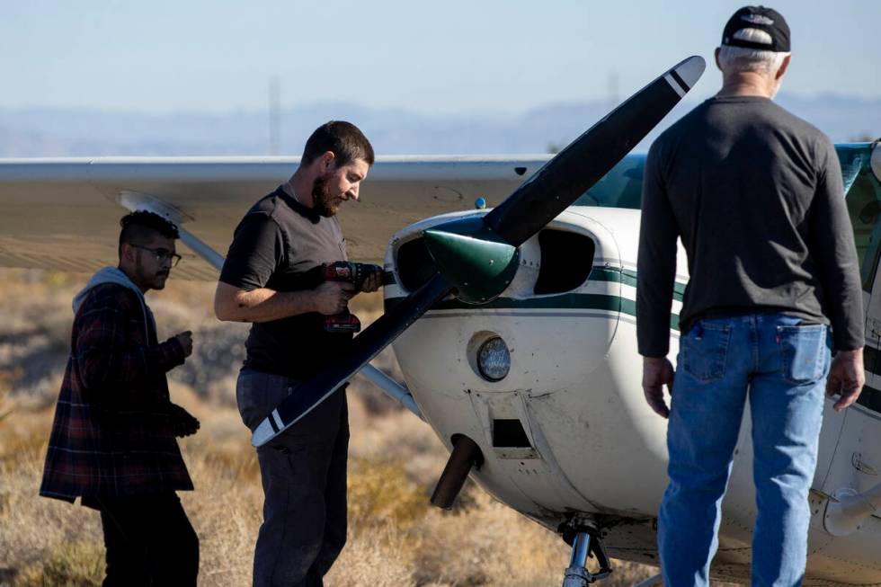 A crew of men, who declined to give their names, work on a plane after it emergency landed on K ...