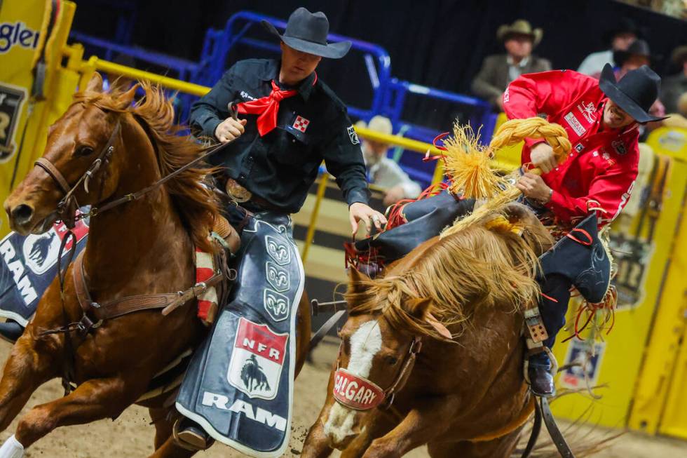 A pickup man helps saddle bronc rider Kade Bruno off of Wild Cherry during round three of the N ...