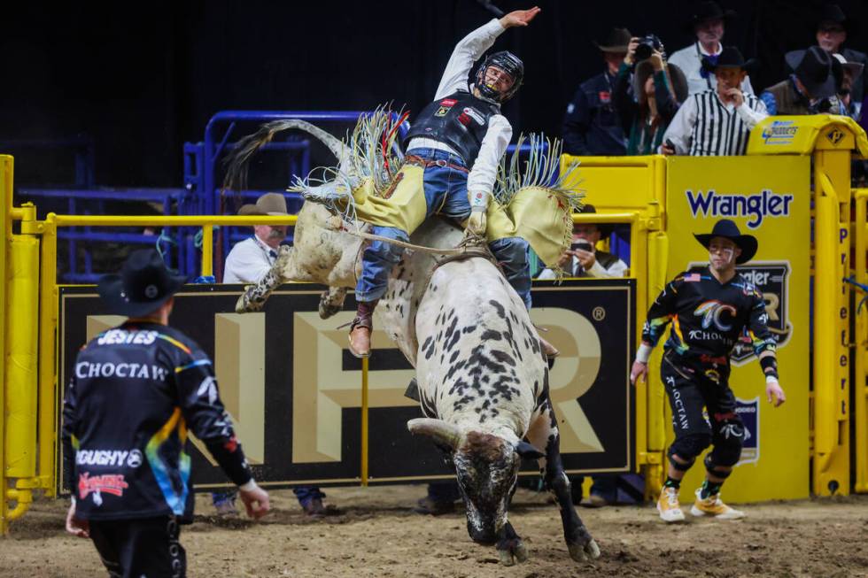 Bull rider Chase Dougherty rides Hot Pop during round three of the National Finals Rodeo at the ...