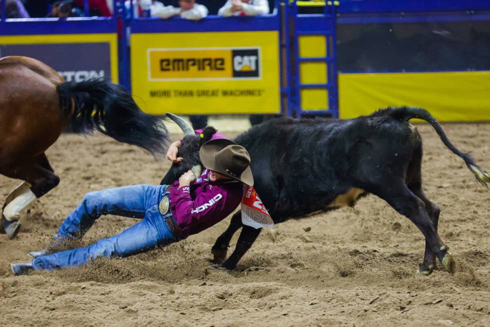 Steer wrestler Scott Guenthner wrestles down a steer during round three of the National Finals ...