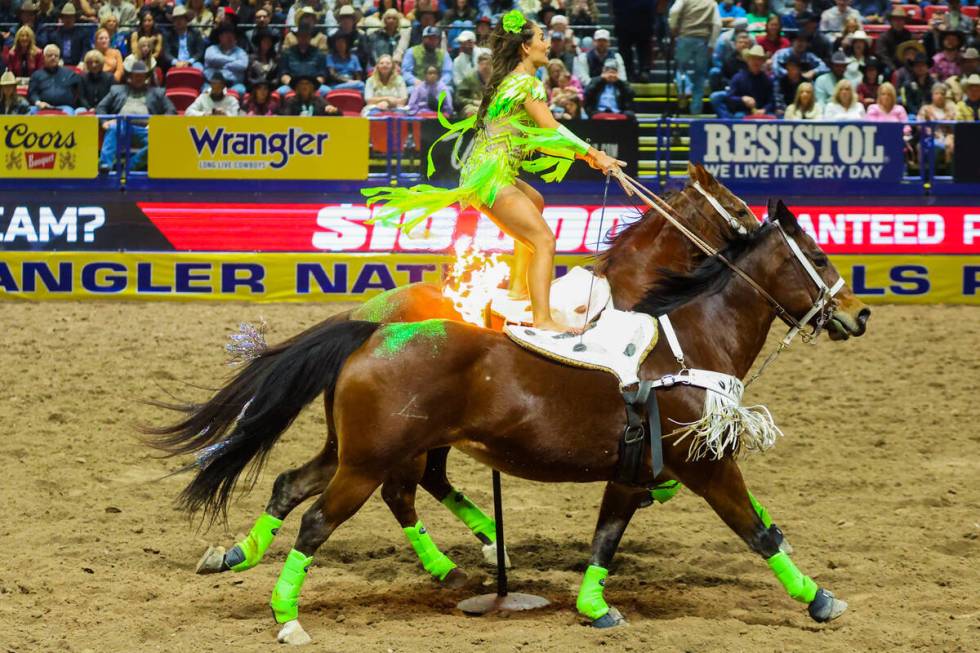 A trick rider rides over fire during round three of the National Finals Rodeo at the Thomas &am ...