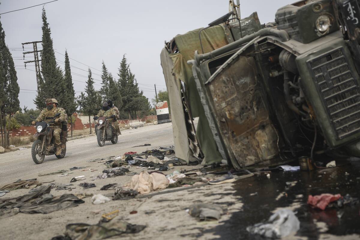 Syrian opposition fighters drive past a damaged government vehicle south of Hama, Syria, on Sat ...