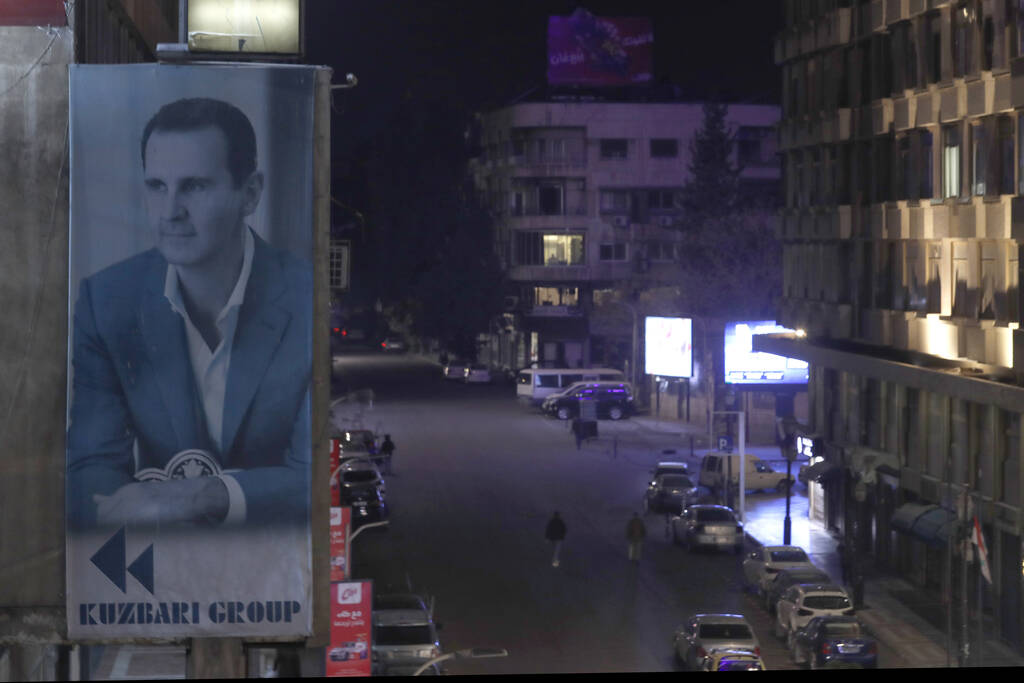 A giant banner of Syrian President Bashar Assad hangs on the facade of a building, as pedestria ...