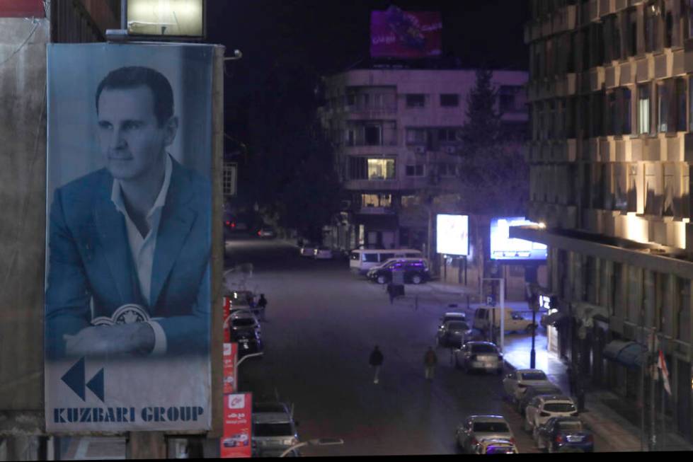 A giant banner of Syrian President Bashar Assad hangs on the facade of a building, as pedestria ...