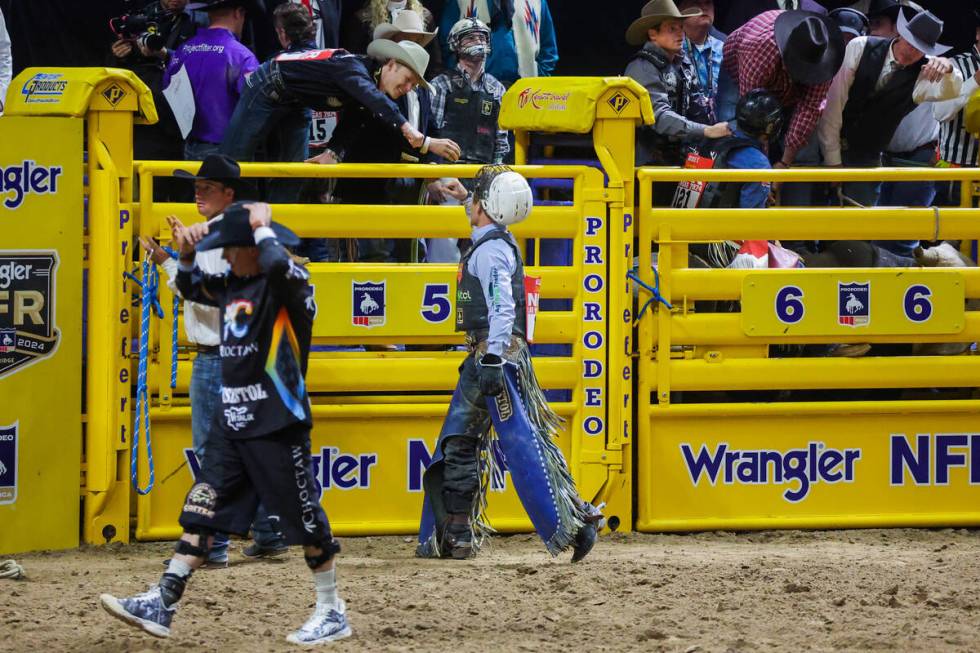 Bull rider Clayton Sellars fist pumps a fellow contestant after his ride during round three of ...