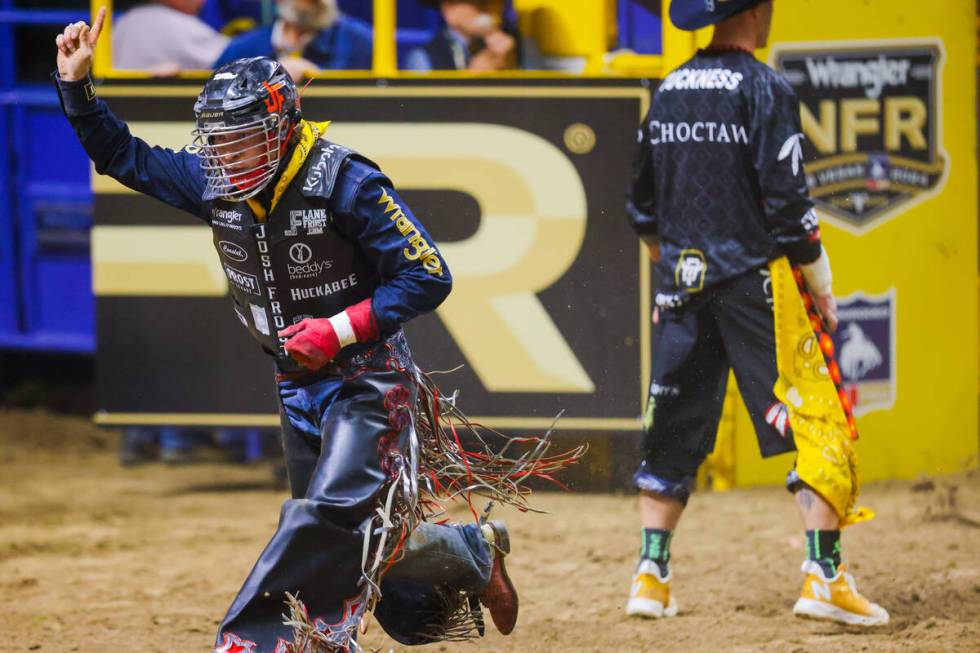 Bull rider Josh Frost celebrates his ride during round four of the National Finals Rodeo at the ...