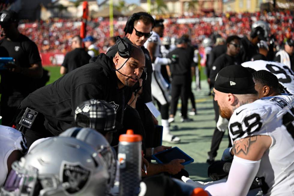 Las Vegas Raiders head coach Antonio Pierce, center, works with defensive players on the sideli ...