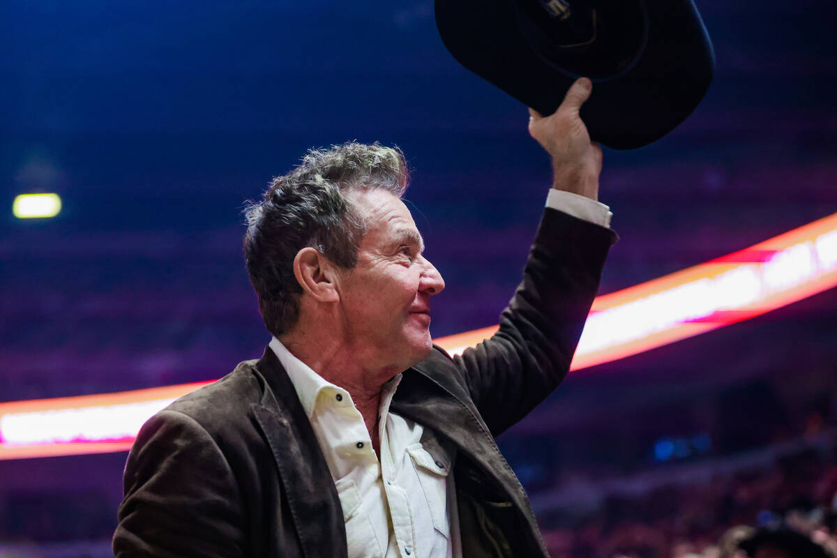 Actor Dennis Quaid tips his hat to the crowd during the final night of National Finals Rodeo at ...