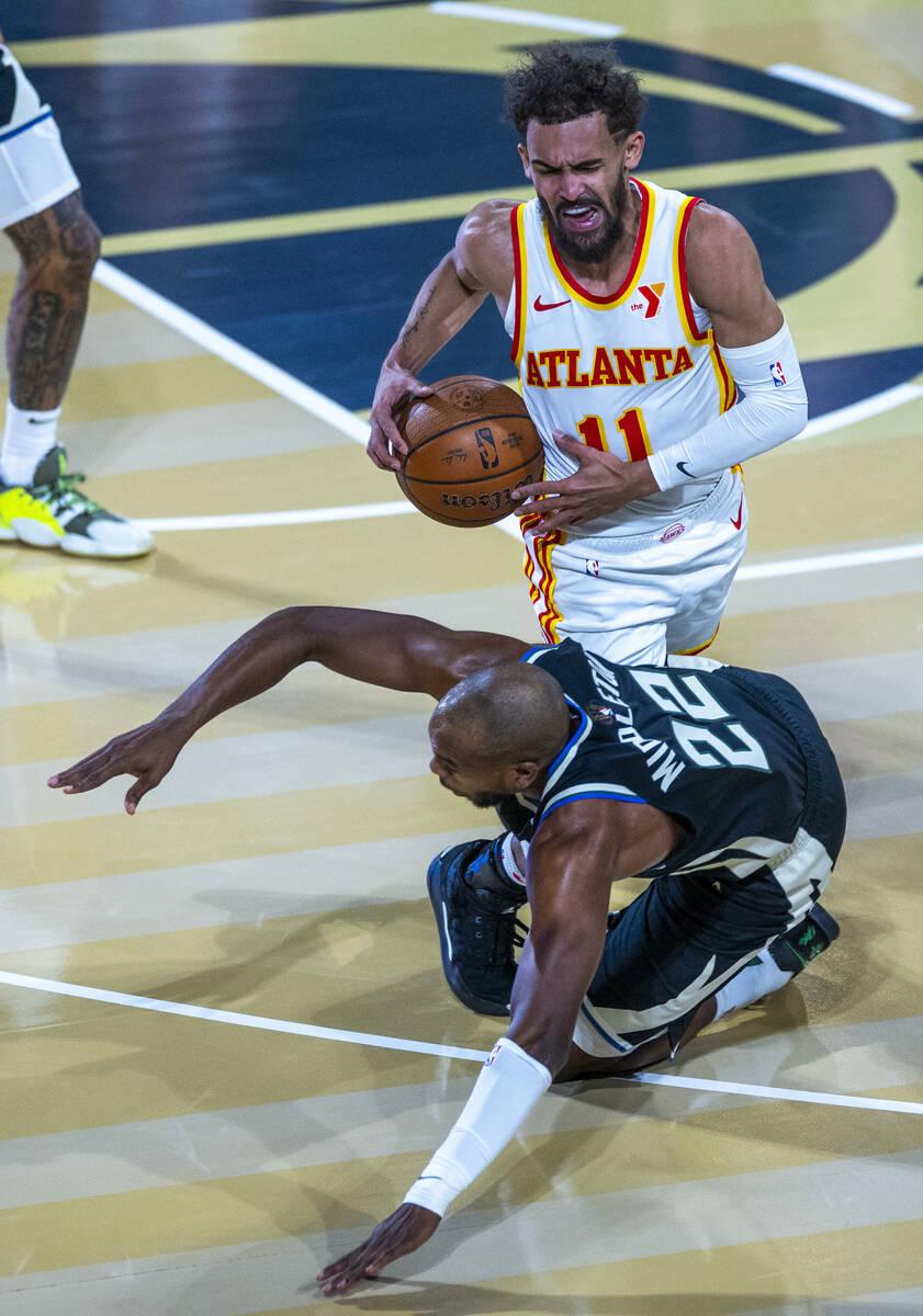 Atlanta Hawks guard Trae Young (11) is run into by Milwaukee Bucks forward Khris Middleton (22) ...