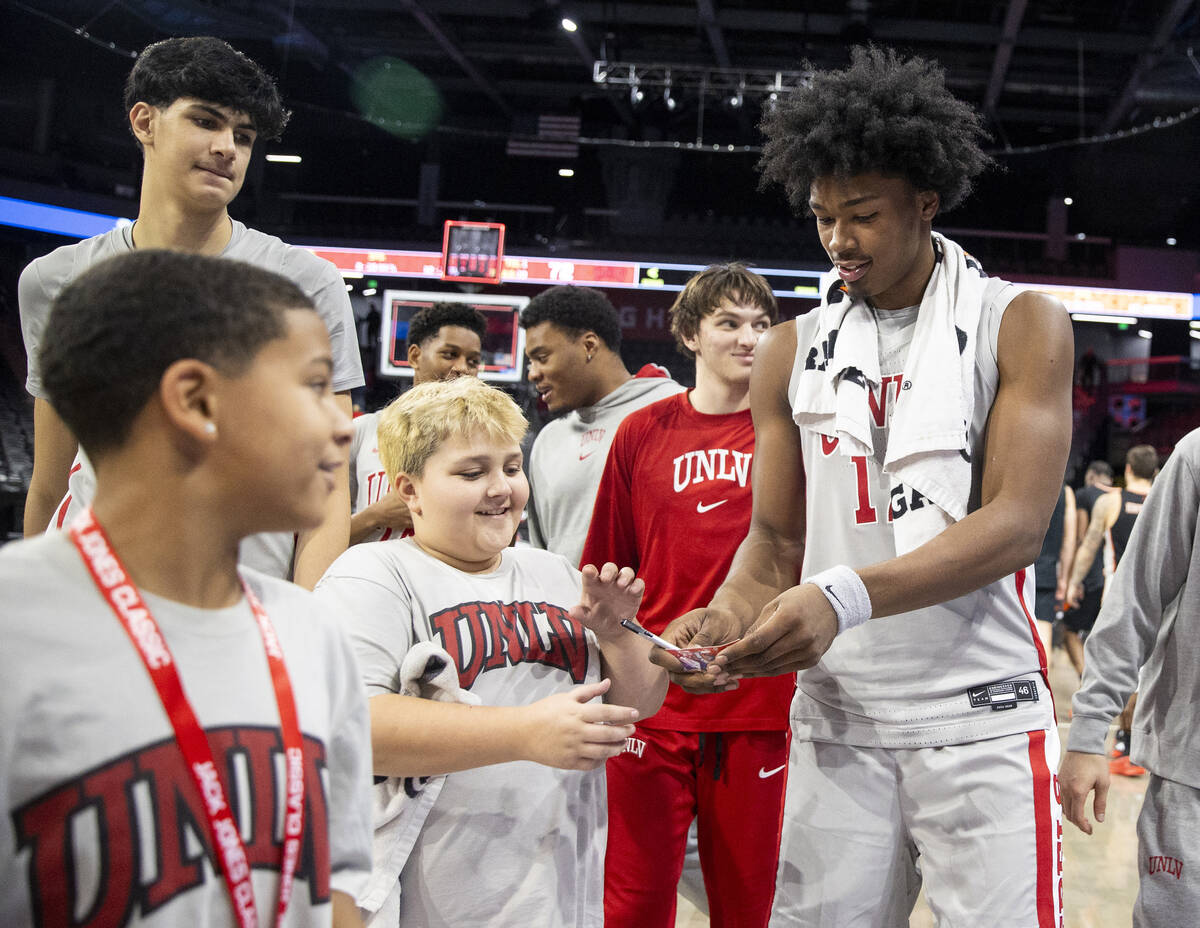 UNLV forward Jacob Bannarbie (12) signs a young fan’s credential after winning the Jack ...