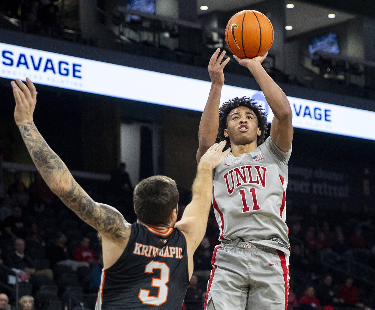 UNLV guard Dedan Thomas Jr. (11) attempts a shot over Pacific Tigers guard Petar Krivokapic (3) ...