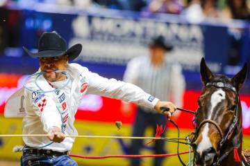 Tie-down roper Shad Mayfield runs from his horse to tie down the calf during round four of the ...