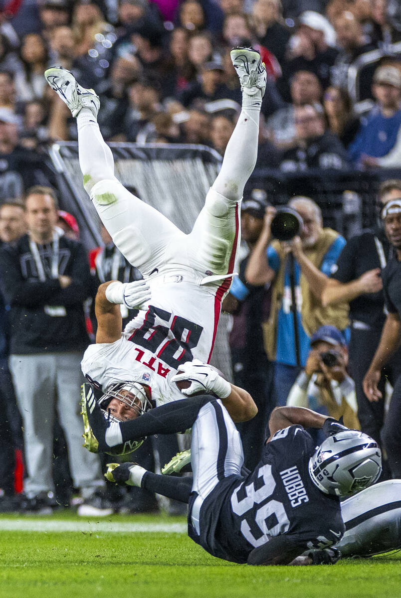 Atlanta Falcons tight end Charlie Woerner (89) flips over Raiders cornerback Nate Hobbs (39) af ...