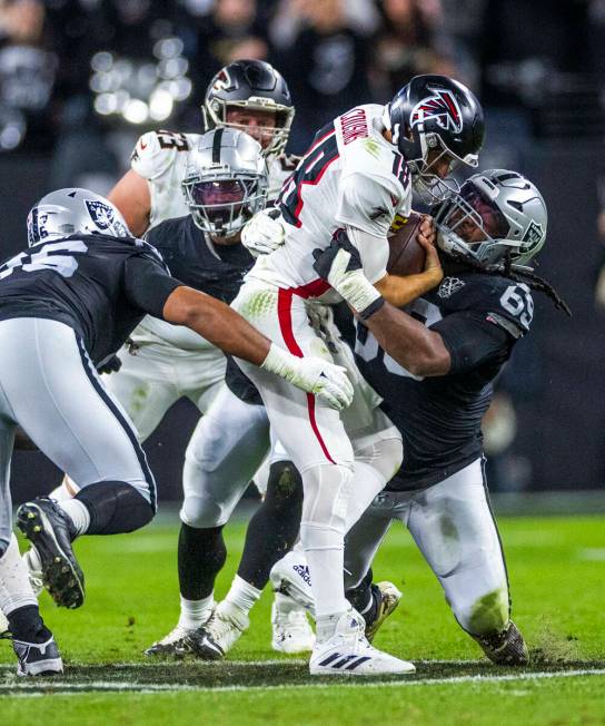 Raiders defensive tackle Adam Butler (69) and defensive tackle Jonah Laulu (96) team up to sack ...