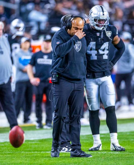 Raiders Head Coach Antonio Pierce grabs his nose beside defensive end K'Lavon Chaisson (44) aga ...