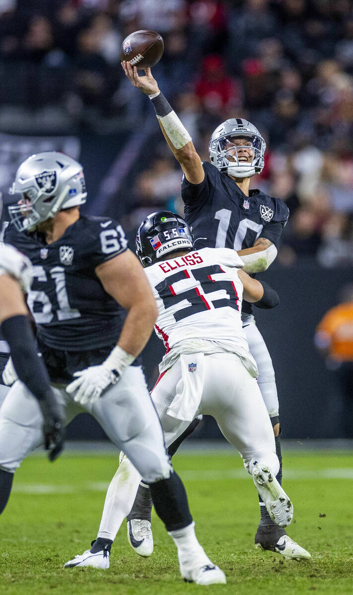 Raiders quarterback Desmond Ridder (10) gets off a pass while being hit by Atlanta Falcons line ...