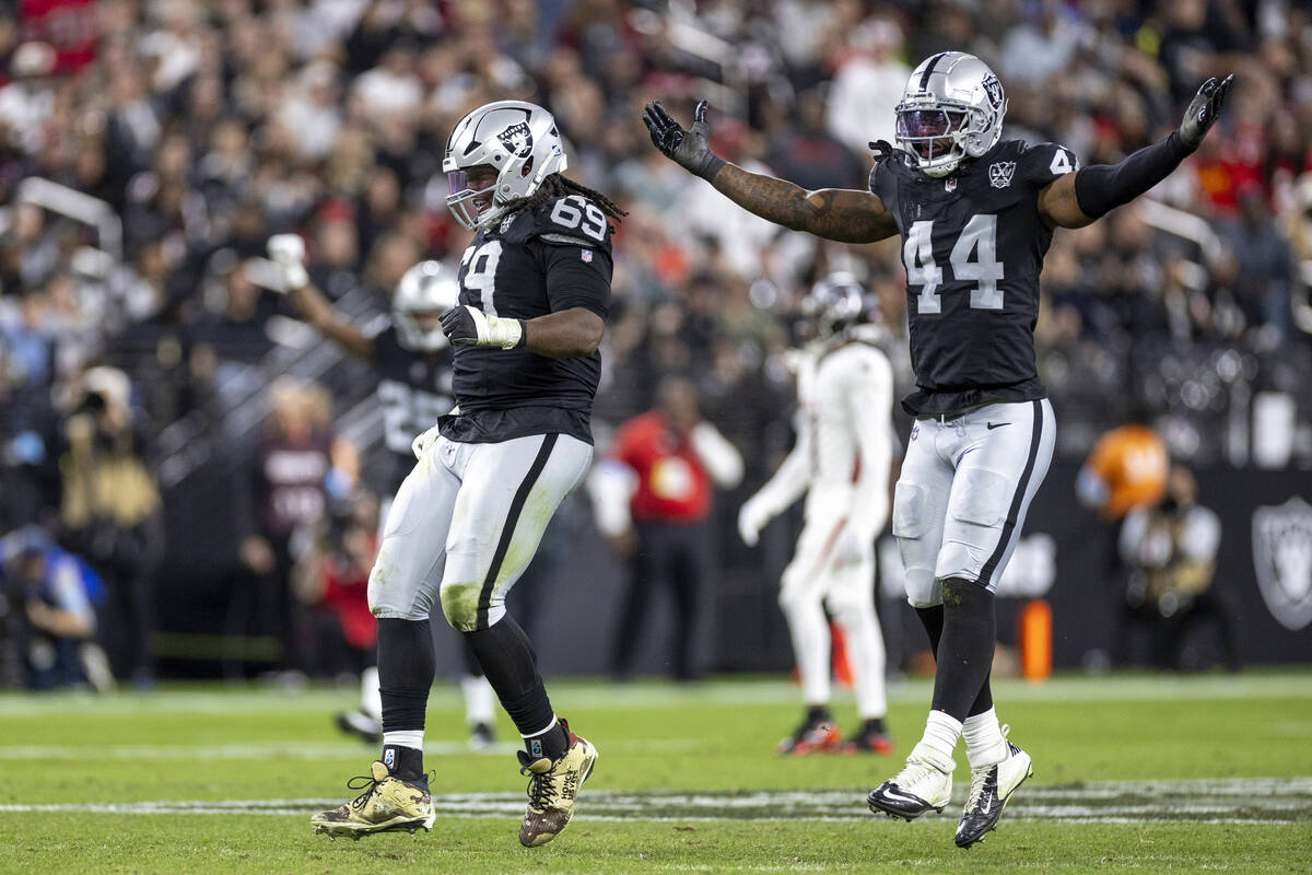 Raiders defensive tackle Adam Butler (69) and Raiders defensive end K'Lavon Chaisson (44) celeb ...