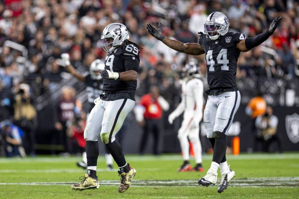 Raiders defensive tackle Adam Butler (69) and Raiders defensive end K'Lavon Chaisson (44) celeb ...