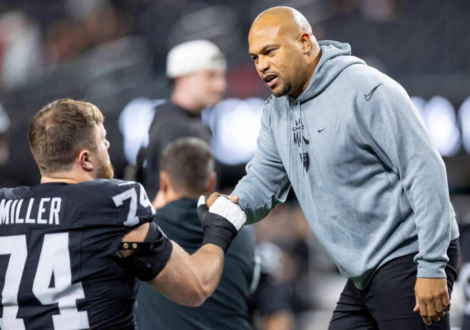 Raiders head coach Antonio Pierce talks to Raiders offensive tackle Kolton Miller (74) before t ...