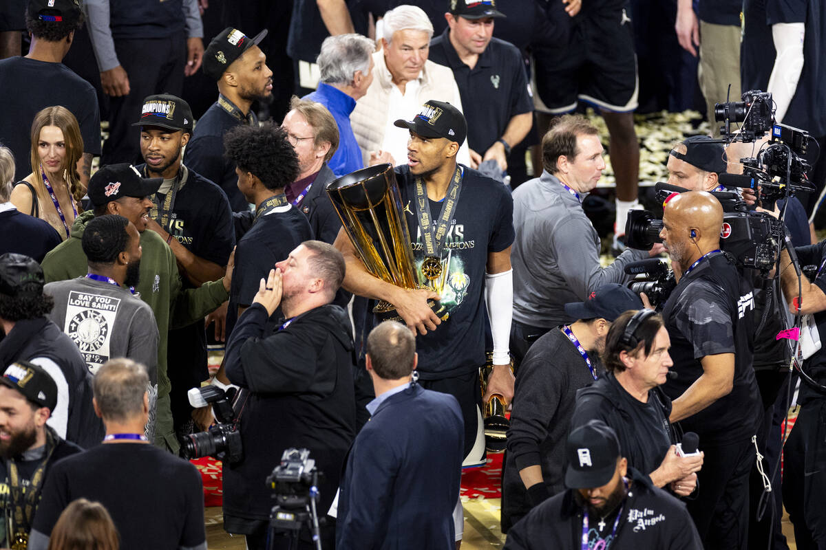 Milwaukee Bucks forward Giannis Antetokounmpo, center, carries the NBA Cup trophy and Most Valu ...