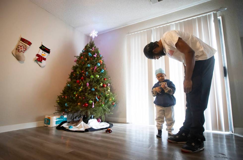 Angelo Crews, right, talks with his son Carmelo Crews, 3, as he plays with a toy that was donat ...